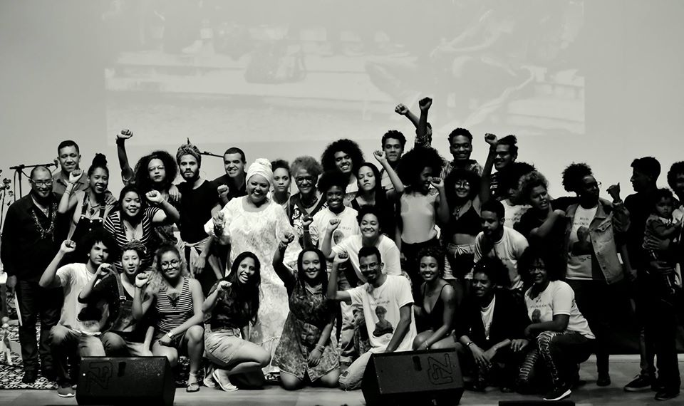 Foto horizontal em preto e branco com diversas pessoas no palco do Centro de Convenções durante evento Novembro Negro