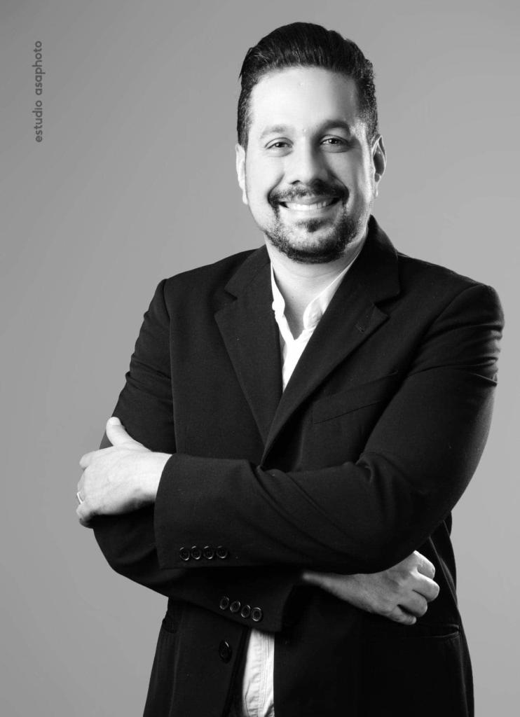 Foto em preto e branco de homem usando terno de braços cruzados
