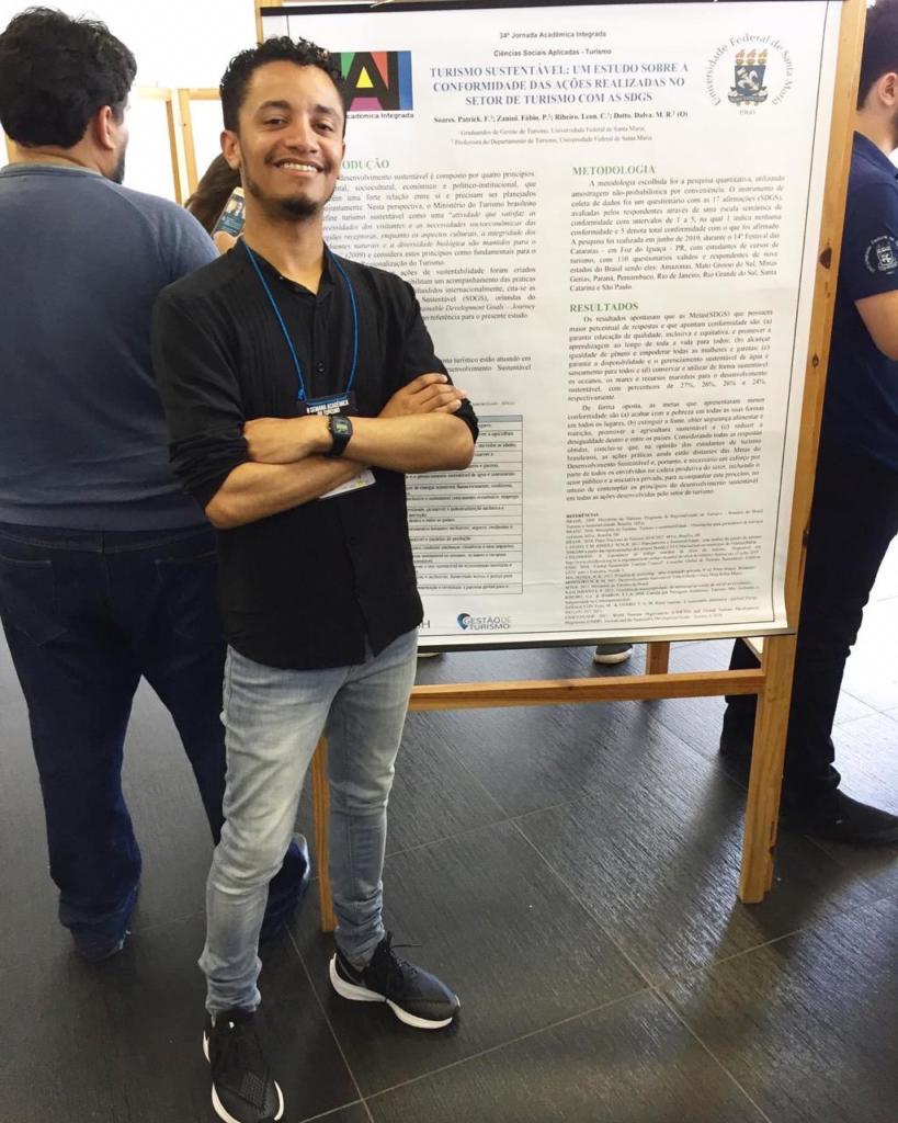 Estudante em pé na frente de um banner da JAI