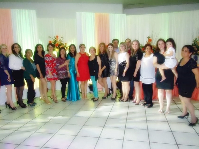 Foto horizontal com diversas mulheres em pé em um salão de festas