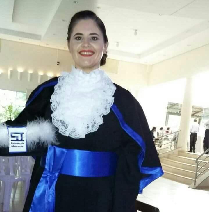 Foto vertical colorida de formanda vestindo beca e segurando capelo