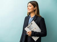 Attractive female entrepreneur holding clipboard with graph while looking away against colored background