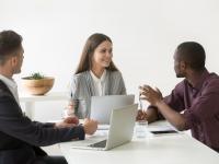 Creative millennial multiracial business team having discussion at office meeting, african manager sharing project ideas with smiling friendly female leader at group briefing, teamwork concept
