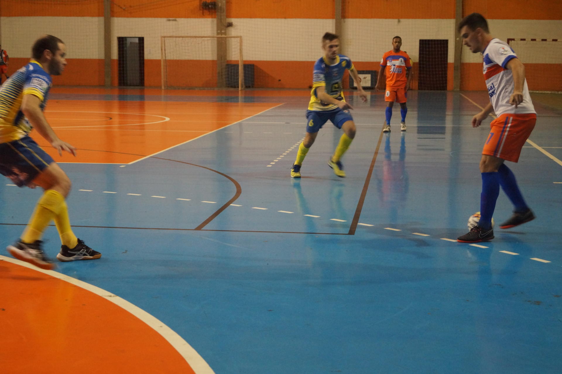 Foto horizontal colorida mostrando jogadores em lance da partida