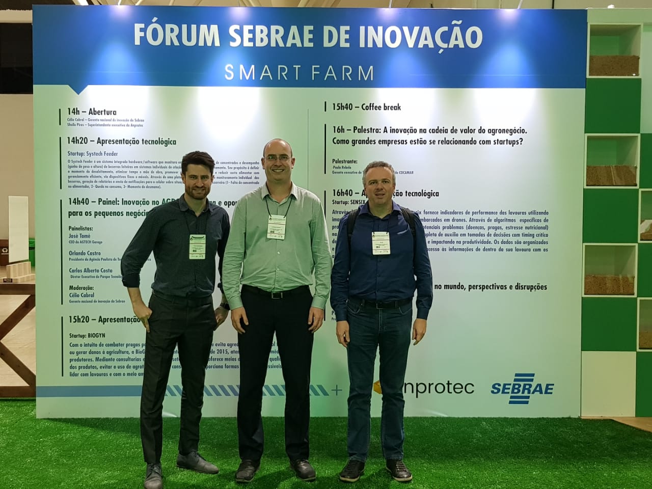 Foto horizontal colorida mostrando Tiago Marchezan, Luciano Schuch e Silon Procath em frente a um banner do Fórum Sebrae de Inovação