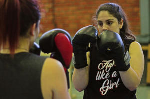Foto com duas mulheres lutando box chinês. Uma delas está de costas e a outra de frente.