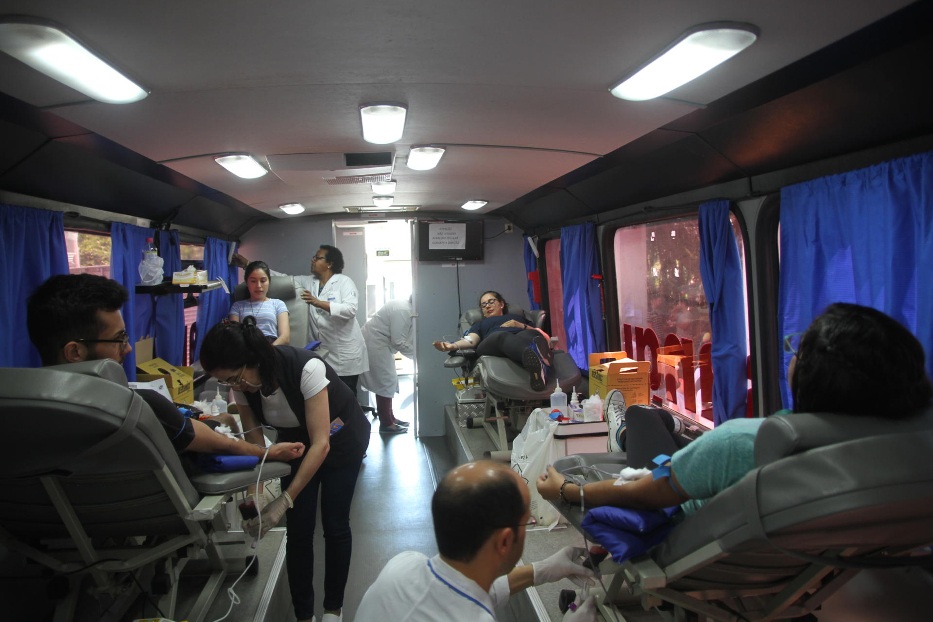 Na imagem é possível ver quatro macas, todas ocupadas com doadores de sangue, e quatro profissionais da saúde