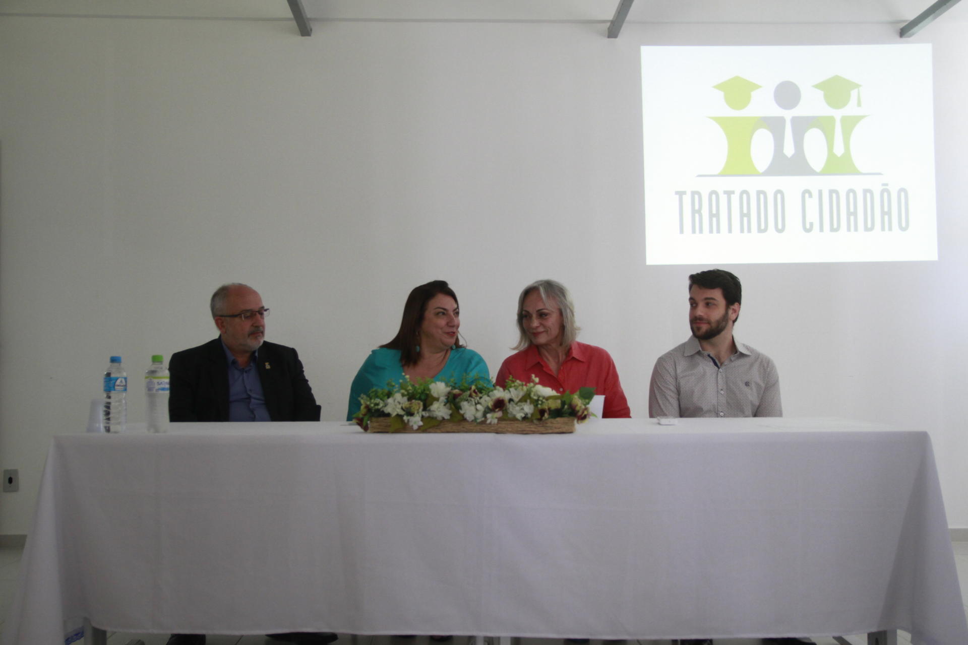 Quatro pessoas sentadas à mesa, incluindo a pró-reitora de Graduação, professora Martha Adaime. Atrás uma projeção com a expressão "Tratado Cidadão"
