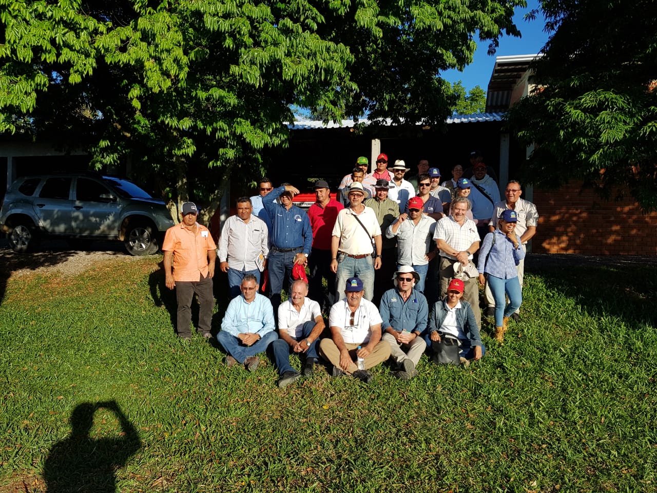 Foto colorida horizontal do grupo de visitantes e membros da UFSM posando, alguns em pé e outros sentados, em uma área ao ar livre