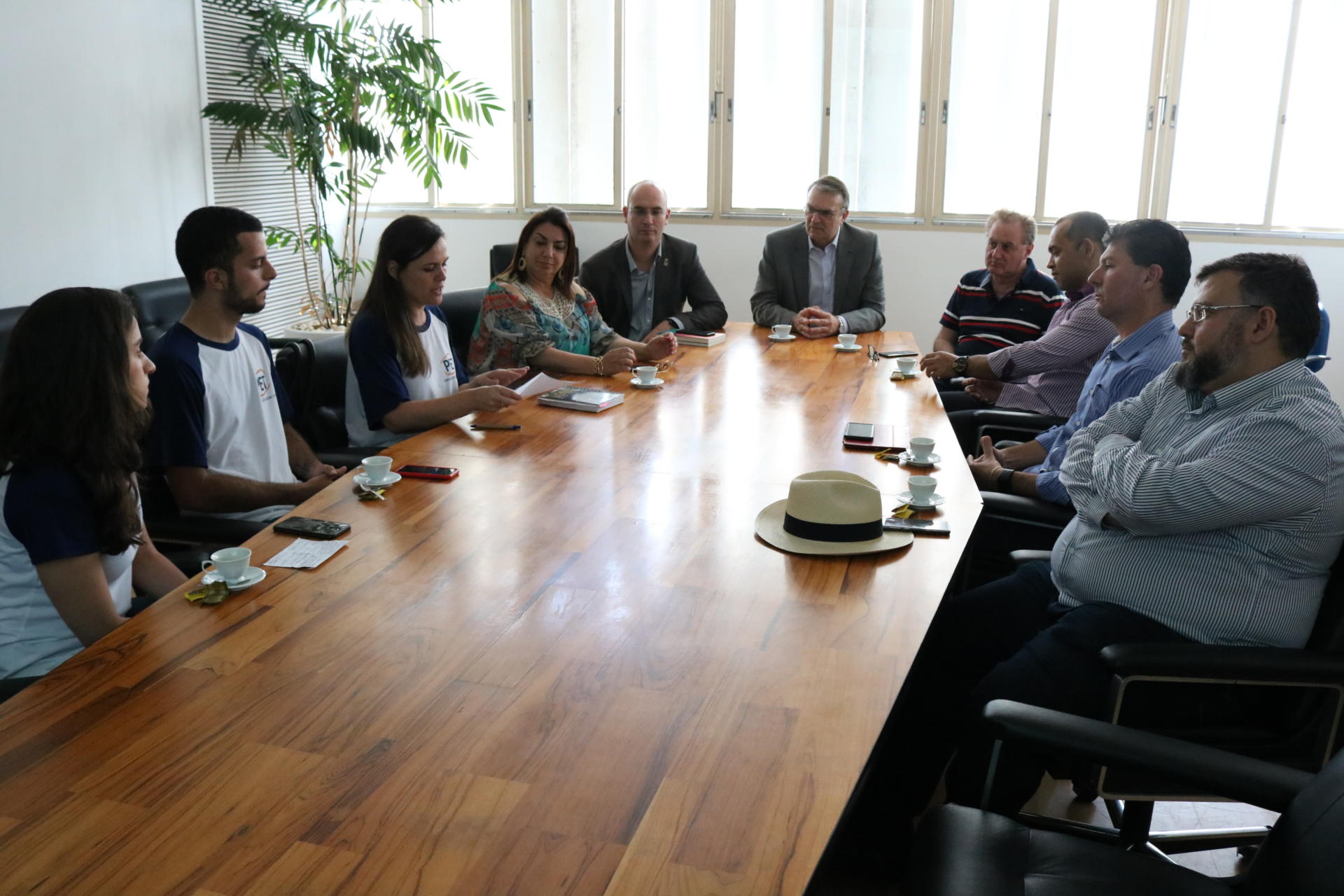 Em torno da mesa do reitor, estudantes, pró-reitores, vice-reitor e o reitor