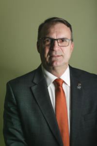 Foto retrato do reitor usando um terno preto e gravata vermelha