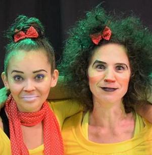 Foto colorida das duas artistas caracterizadas como "as irmãs pulgas", com rosto pintado, roupa amarela e laços vermelhos nos cabelos