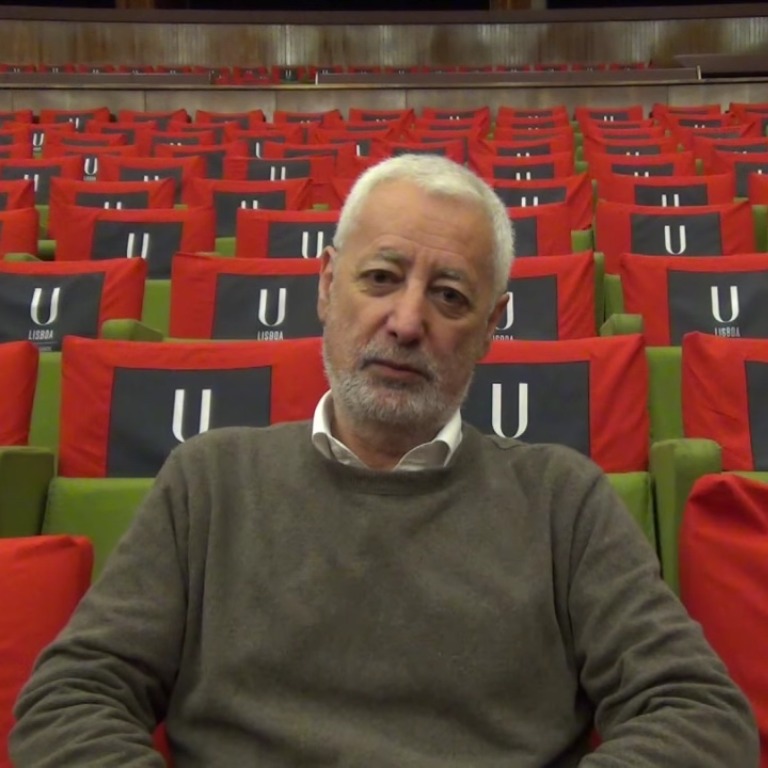 Foto do professor sentado em um auditório